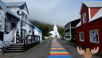 Innenstadt von Seyðisfjörður mit der Regenbogenstraße, der blauen Kirche und historischen Häuser. - Downtown Seyðisfjörður with the rainbow street, the blue church and historical houses.